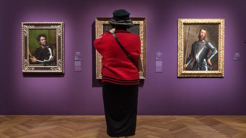 Eine Frau in roter Jacke und schwarzem Hut fotografiert im Städel Museum Bilder des italienischen Malers Tizian.