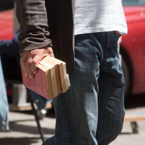 Ein Mann trägt mehrere Bücher in einer Hand