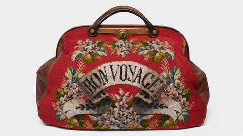 Rote Reisetasche aus Stoff mit dem Schriftzug "Bon Voyage" auf der Vorderseite