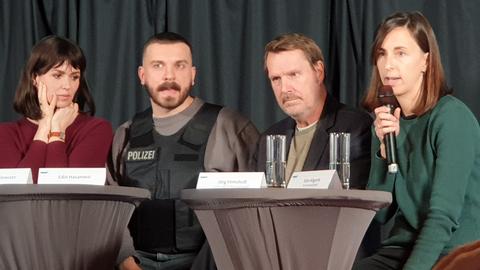 Vier Menschen auf einem Podium, einer trägt eine Polizei-Uniform