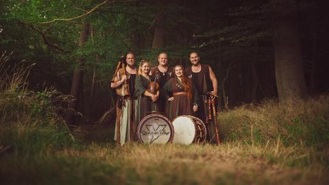 Die Bandmitglieder von "Unvermeydbar" stehen vor einem Wald. 