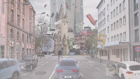 Das Bild zeigt eine Animation vom Eschenheimer Tor. Zu sehen sind verschiedene Autos und Straßenschilder, die vor dem mittelalterlichen Turm durch die Luft fliegen.