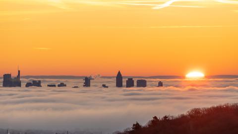 Die Hochhäuser der Frankfurter Skyline ragen am Morgen bei Sonnenaufgang aus dem Nebel.