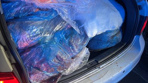 Das Bild zeigt den geöffneten Kofferraum eines silbernen Autos. Darin befinden sich mehrere große Tüten mit rohem Hackfleisch.