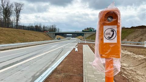 Foto einer noch nicht fertigen Autobahn. Im Vordergrund steht groß eine orangfarbene SOS-Säule, welche noch eine Plastikschutztüte übergestülpt hat..