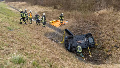 Auto im Graben, daneben Feuerwehrkräfte