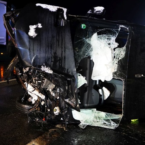 Ein Auto liegt beschädigt auf der Seite auf der Autobahn