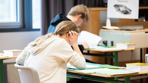 Kinder sitzen an einem Tisch und schreiben eine Prüfung. 