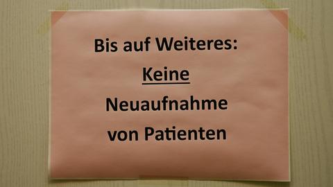 Auf eine Tür ist ein Blatt geklebt mit der Aufschrift: "Bis auf Weiteres: Keine Neuaufnahmen von Patienten"