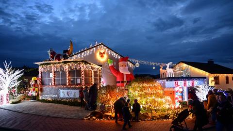 Ein mit Aufblas-Weihnachtsmann, Rentier-Schlitten und tausenden Lichtern geschmücktes und im Dunklen erstrahlendes Haus