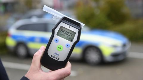 Ein Polizist misst den Atemalkoholgehalt eines Autofahrers mit einem Alkoholtester, um festzustellen, ob er möglicherweise unter Alkoholeinfluss steht.