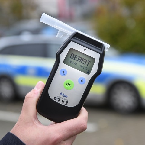 Ein Polizist misst den Atemalkoholgehalt eines Autofahrers mit einem Alkoholtester, um festzustellen, ob er möglicherweise unter Alkoholeinfluss steht.