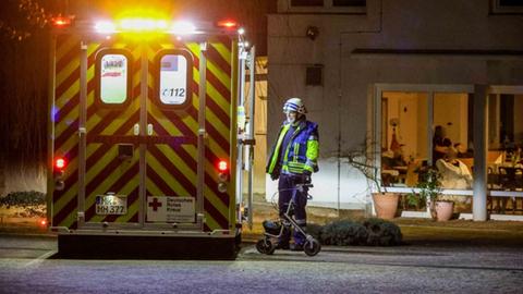 Feuerwehrmann mit Gehwagen vor einem Rettungswagen in der Nacht