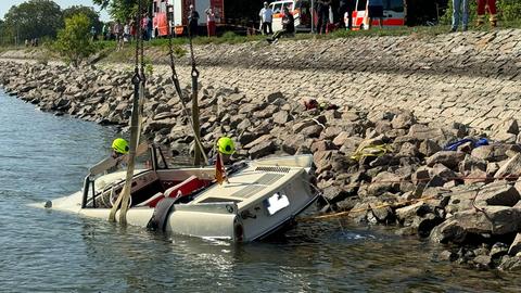 Eine Art Auto liegt im Wasser und hängt an einem Kran