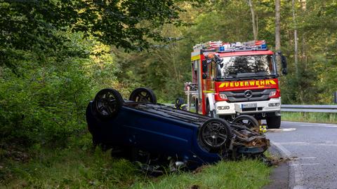 Unfallstelle bei Linsengericht - ein Auto hat sich überschlagen und liegt im Straßengraben auf dem Dach. Im Hintergrund ein Einsatzfahrzeug der Feuerwehr.