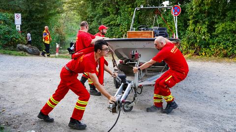 Einsatzkräfte mit einem roten Schlauchboot am Seeufer.