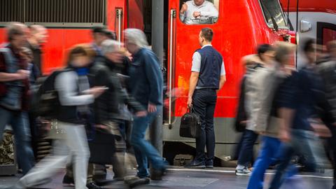 Bahnreisende und Lokführer am Bahnsteig