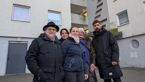 Mustafa Zeyrek (re.) und Beata Bayram (Mitte) stehen mit anderen Bewohnern vor dem Hochhaus Nummer 46. 