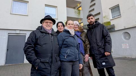 Mustafa Zeyrek (re.) und Beata Bayram (Mitte) stehen mit anderen Bewohnern vor dem Hochhaus Nummer 46. 