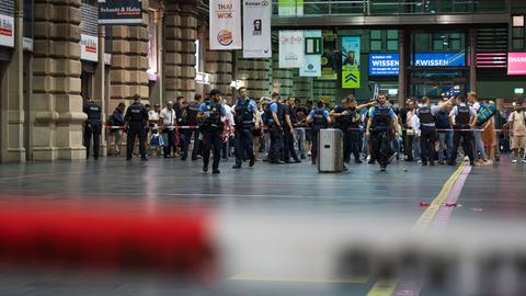 Frankfurter Hauptbahnhof: Zahlreiche Reisende hinter Absperrband in Abfahrthalle. Davor stehen bis zu zehn Polizisten.