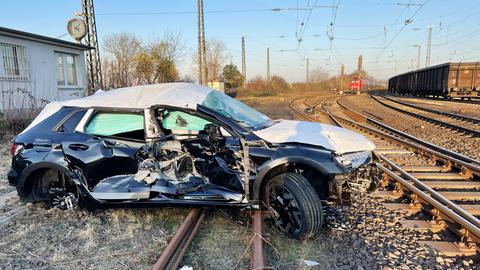 Teils noch mit Folie abgedeckter Neuwagen, demoliert auf Schienen stehend