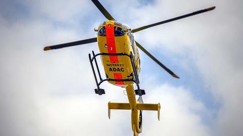 Gelber, fliegender Hubschrauber mit der Aufschrift "ADAC Luftrettung", von unten fotografiert.