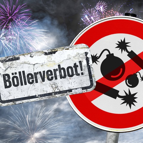 Warnschild mit durchgestrichenen Feuerwerkskörpern, Schild mit Aufschrift "Böllerverbot", im Hintergrund Feuerwerksraketen