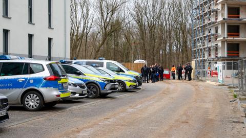 Polizeiautos und Polizisten stehen vor einer Baustelle in Frankfurt-Bockenheim.