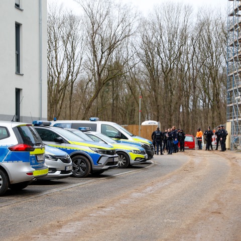 Polizeiautos und Polizisten stehen vor einer Baustelle in Frankfurt-Bockenheim.