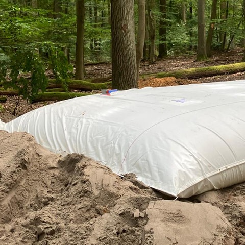 Ein großer mit Wasser gefüllter Sack liegt auf einer Sandgrube.