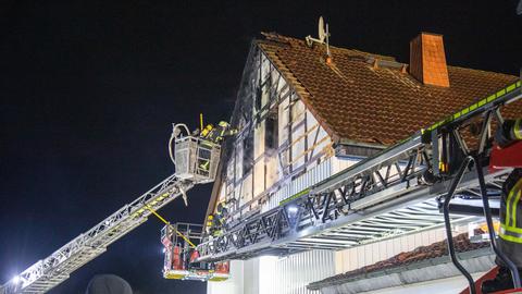 Einsatzkräfte der Feuerwehr bekämpfen auf zwei Leiterwagen den Brand eines Fachwerkhauses