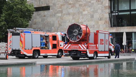 Feuerwehrwagen und Einsatzfahrzeug mit Entlüftung neben Gebäude und Teich