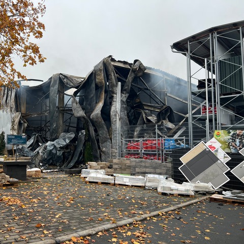 Eine teilweise eingestürzte Lagerhalle, teilweise verkohlt.