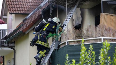 Feuerwehrmann klettert über Leiter auf Balkon