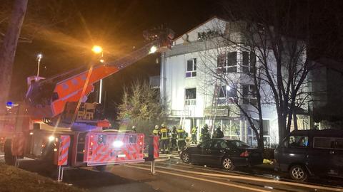 Ein Feuerwehrwagen mit Drehleiter nachts an einem mehrstöckigen Haus