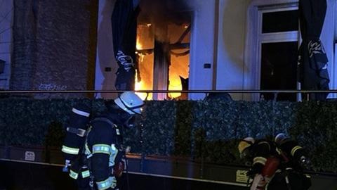 Flammen in einem Gebäude, davor ein Feuerwehrmann