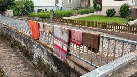 Handtücher höngen an einem Geländer - darunter ein kanalisierter Bach