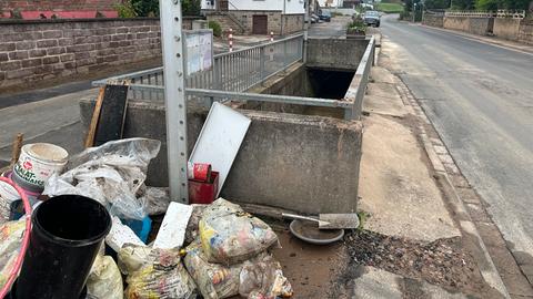 Gelbe Säcke voll mit Müll - dahinter ein Schacht, dort fließt der Bach kanalisiert.