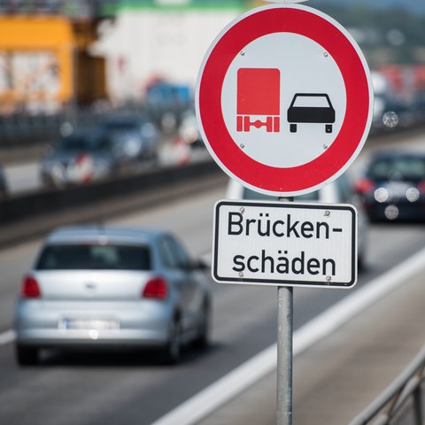 Schild "Brückenschäden" auf Brücke mit Verkehr