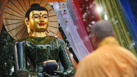 Ein buddhistischer Mönch steht vor einem Jade Buddha