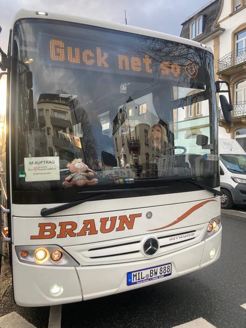 Busfahrerin in einem weißen Bus mit der Anzeige "Guck net so"