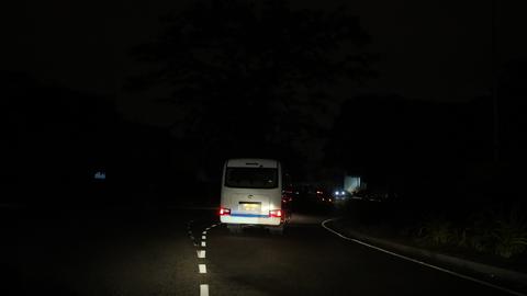 Ein silberner Bus steht mitten in der Nacht auf einer Straße im Dunkeln, nur seine Rücklichter leuchten