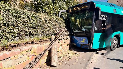 Ein Linienbus ist gegen eine Mauer gefahren. Die Front ist beschädigt.