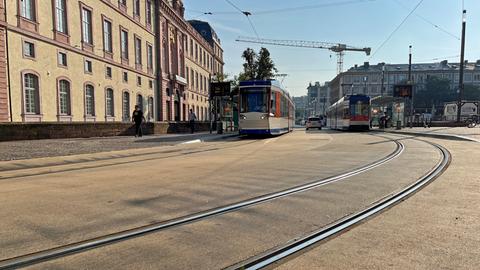 Straßenbahnen fahren vor dem Darmstädter Schloss über den neuen Straßenbelag "Busphalt".