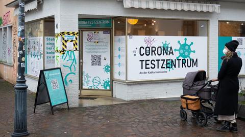 Eine Frau mit Kinderwagen steht vor einem Corona-Testzentrum.