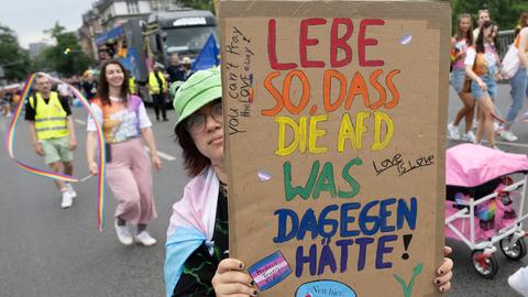 CSD-Teilnehmende mit Plakat mit der Aufschrift: Lebe so, dass die AfD was dagegen hätte. Love is love. 