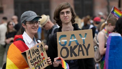 CSD-Teilnehmende mit Plakaten: "Gay okay" und "1 Hug if you're gay"