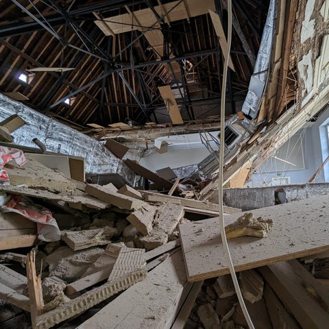 Aus der Froschperspektive fotografiert: eine herabgestürzte Decke. Oben klafft ein Riesenloch, unten sehr viel Schutt.