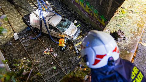 Einsatzkräfte bergen ein auf Bahngleise gestürztes Auto