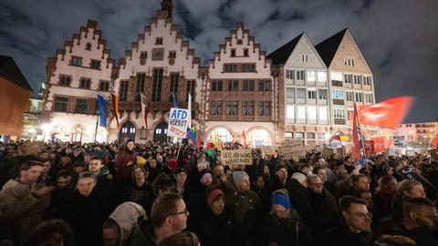 Im Hintergrund der Römer. das Frankfurter Rathaus, der Vordergrund ist mit Menschen gefüllt, die Plakate schwenken.